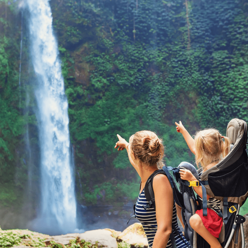Ecoturismo com crianças: 10 Destinos no brasil 1 mãe fazendo ecoturismo com criança apontando para uma cachoeira na chapada dos veadeiros